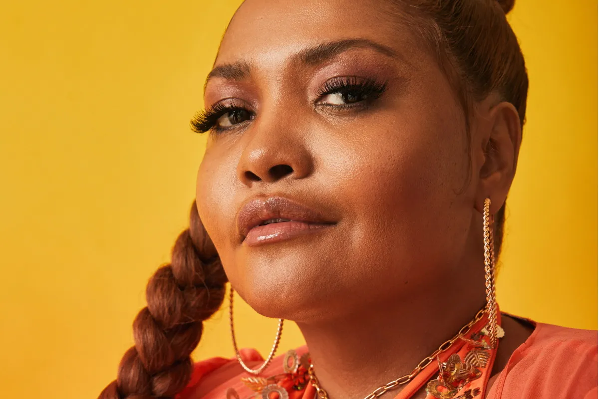 Imagem de Gaby Amarantos com cabelo trancado em um ambiente de estúdio de rádio