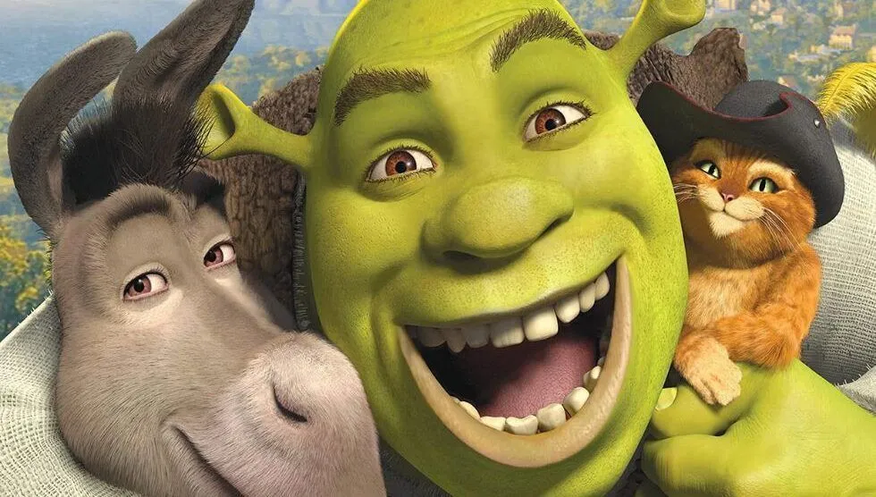 Imagem da equipe da Rádio Estação Plus ao lado de um pôster de Shrek.
